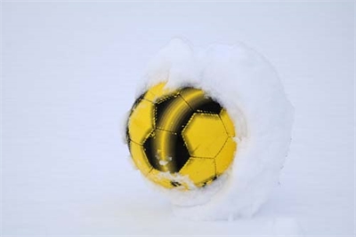 En fotball innpakket i snø på snølagt bane